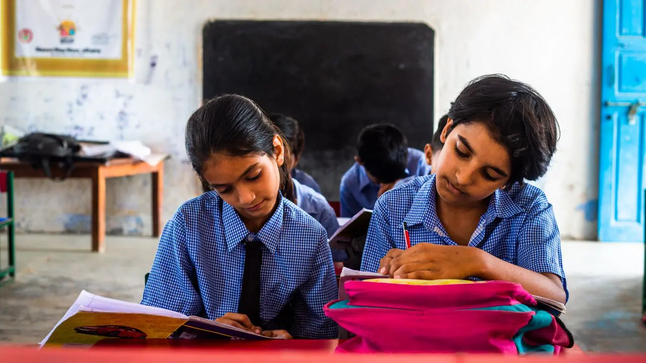 Two students writing in their notebooks