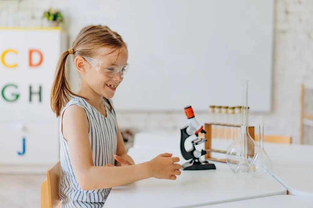 A girl in safety goggles smiling at her science experiment