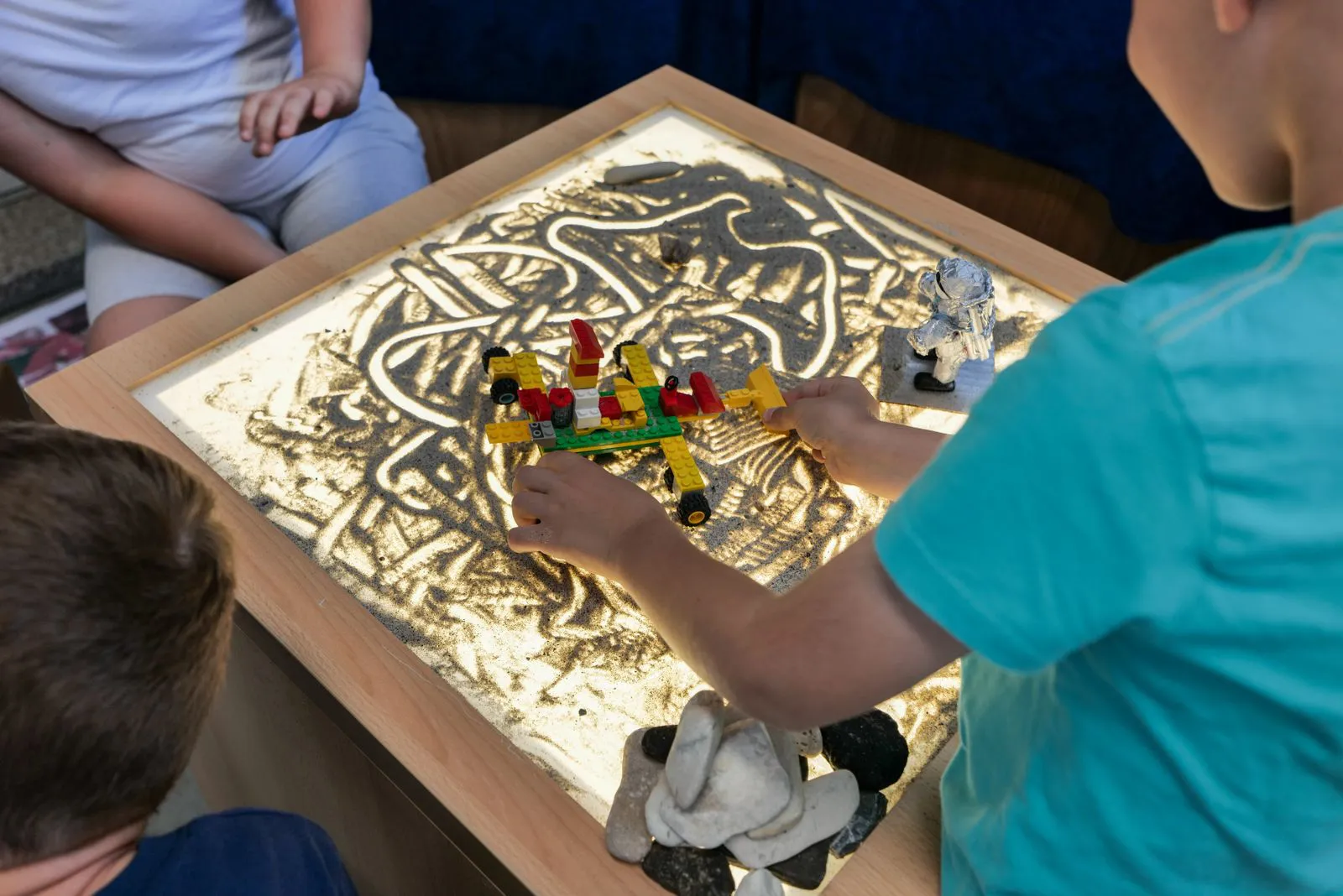 Young children building on a glowing light table in a darkened room