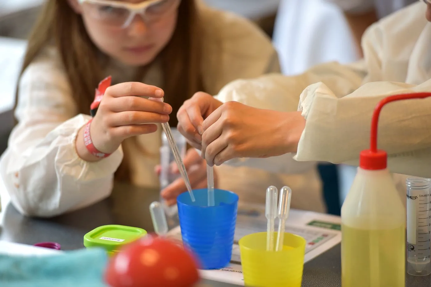 Students in safety glasses running an experiment in the science lab