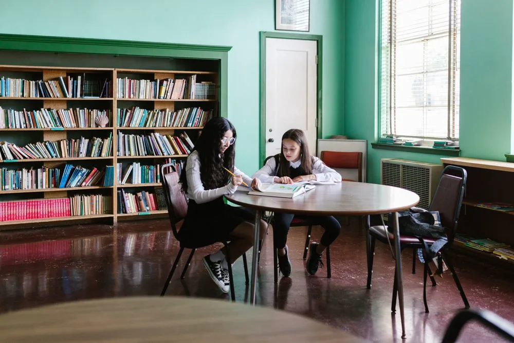 Two students studying at a round table in the library