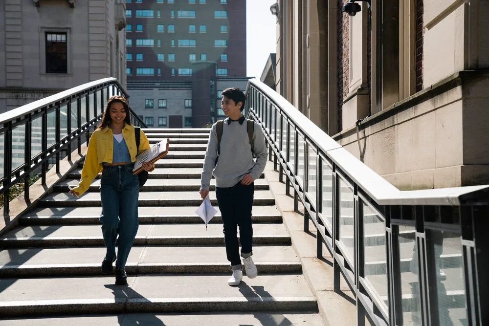 Two senior students walking through the campus with their folders
